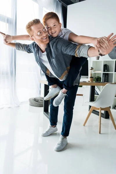 Glücklicher Vater gibt Sohn zu Hause Huckepack — Stockfoto