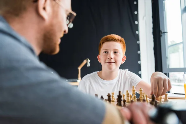 Father and son playing chess and looking at each other at home — Stock Photo