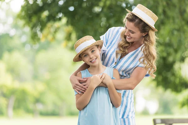Smiling blonde mother and daughter in straw hats — Stock Photo