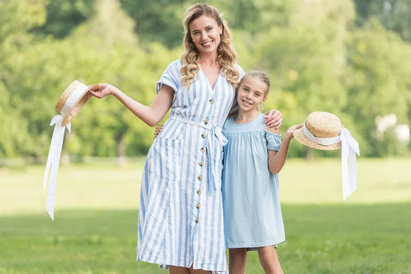 Cheerful mother and daughter posing with straw hats together — Stock Photo