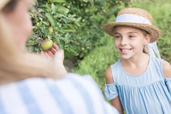 Maman et fille adorable souriante cueillant des pommes ensemble — Photo de stock