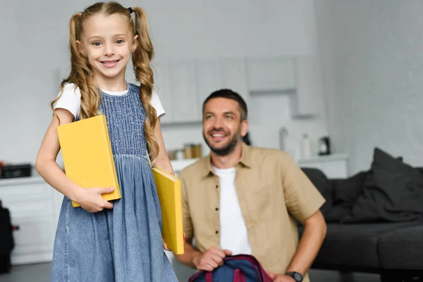 Foyer sélectif du petit enfant avec des livres et père derrière à la maison, concept de retour à l'école — Stock Photo