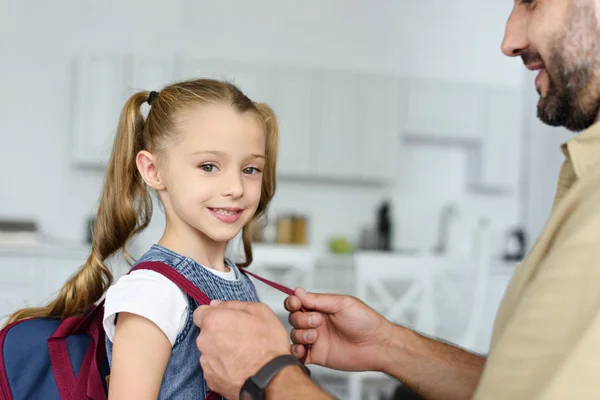 Visione parziale del padre che aiuta la figlia a indossare lo zaino a casa, concetto di ritorno a scuola — Foto stock
