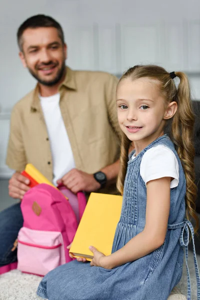Enfoque selectivo de la mochila de embalaje hija y padre para el primer día en la escuela, volver al concepto de la escuela - foto de stock