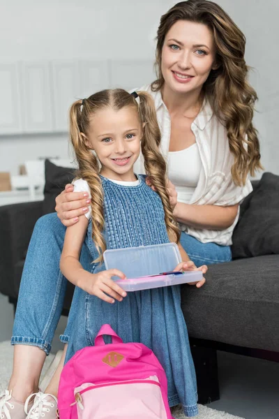 Lächelnde Mutter und kleine Tochter mit Schulsachen und Rucksack zu Hause, zurück zum Schulkonzept — Stockfoto