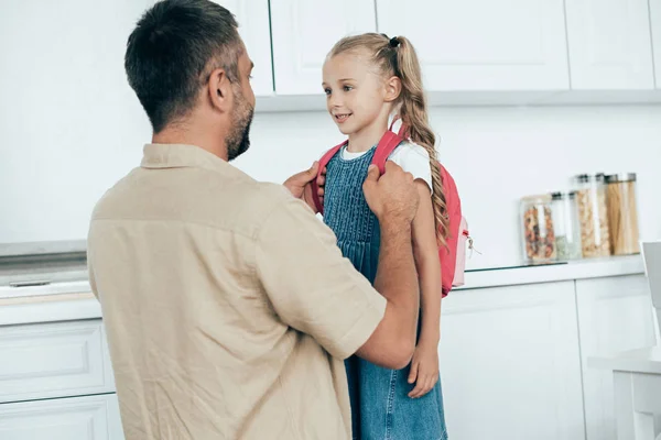 Retrato de pai sorridente e filha pequena com mochila em casa, de volta ao conceito de escola — Fotografia de Stock