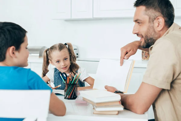 Smiling father and kids doing homework together at home — Stock Photo