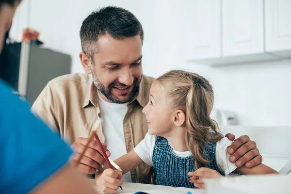 Lächelnder Vater und Kinder bei gemeinsamen Hausaufgaben zu Hause — Stockfoto