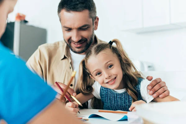 Sorrindo pai e filhos fazendo lição de casa juntos em casa — Fotografia de Stock