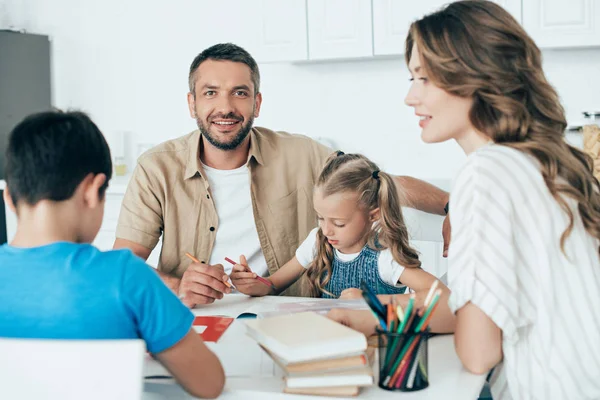 Parents helping children with homework at table at home — Stock Photo