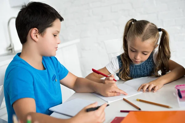 Brother and sister doing homework together at table at home — Stock Photo