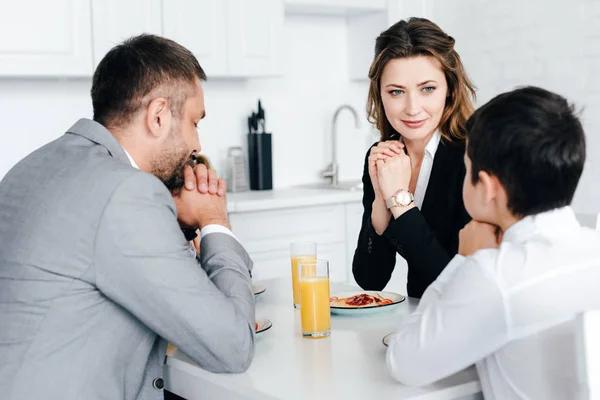 Vue partielle de la famille priant ensemble pendant le petit déjeuner à la maison — Photo de stock