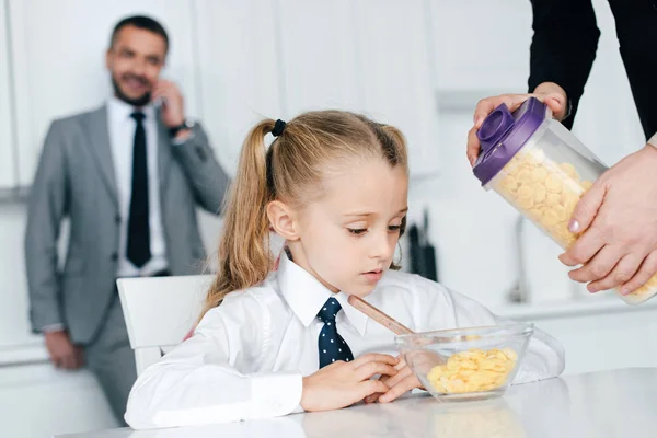 Selektiver Fokus des Kindes in Schuluniform am Tisch mit Frühstück und Eltern zu Hause, zurück zum Schulkonzept — Stockfoto