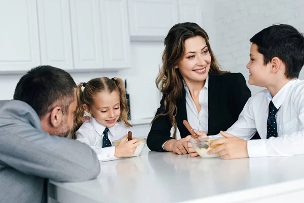 Famiglia in giacca e cravatta e uniforme scolastica fare colazione in cucina insieme — Foto stock
