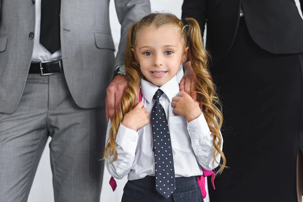 Recortado disparo de los padres en trajes y sonriente niño en uniforme escolar con mochila, volver al concepto de la escuela - foto de stock