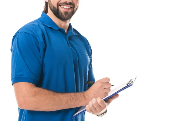 Обрізаний знімок усміхненого чоловіка доставки, що пише на кишені, ізольований на білому — стокове фото