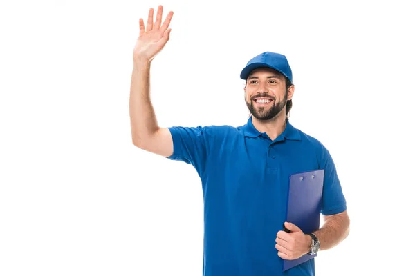 Feliz joven repartidor hombre sujetando portapapeles y agitando la mano aislado en blanco - foto de stock