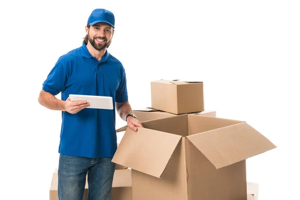 Joven repartidor utilizando tableta digital y sonriendo a la cámara aislada en blanco - foto de stock