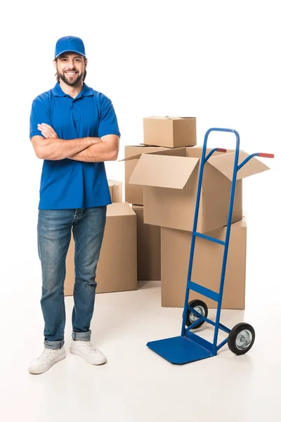 Confident delivery man standing with crossed arms and smiling at camera isolated on white — Stock Photo