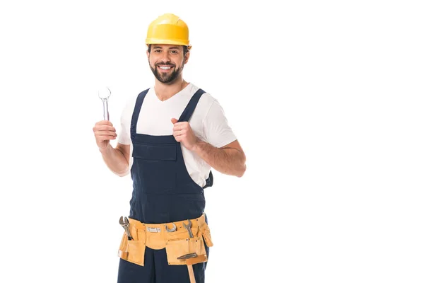 Felice operaio tenendo chiave inglese e sorridendo alla fotocamera isolata su bianco — Foto stock