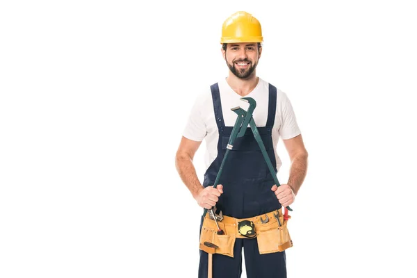 Gutaussehender, glücklicher Reparateur im Werkzeuggurt, der einen verstellbaren Schraubenschlüssel in der Hand hält und isoliert auf weiß in die Kamera lächelt — Stockfoto