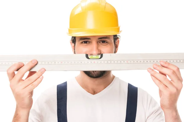 Handsome construction worker in hard hat holding level tool and looking at camera isolated on white — Stock Photo