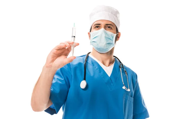 Vista de ángulo bajo del médico en la jeringa de sujeción de máscara médica y mirando hacia arriba aislado en blanco - foto de stock