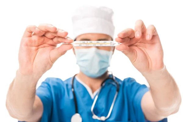 Крупный план врача в медицинской маске, держащего термометр изолированным на белом — стоковое фото