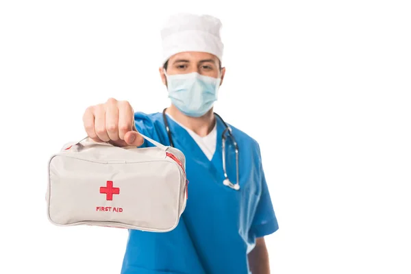 Visão de perto do médico em máscara médica segurando kit de primeiros socorros isolado em branco — Fotografia de Stock