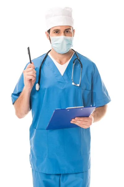 Doctor in medical mask holding clipboard with pen and looking at camera isolated on white — Stock Photo