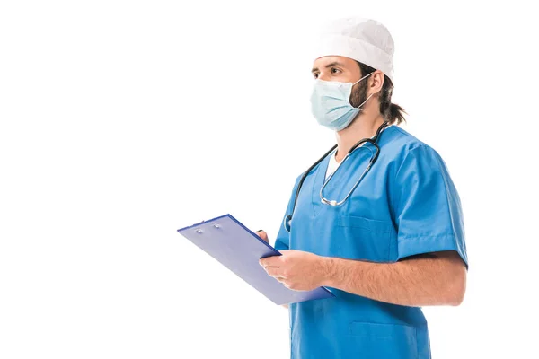 Surgeon in medical mask writing on clipboard isolated on white — Stock Photo