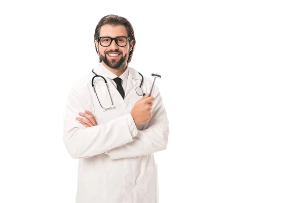 Beau médecin barbu en manteau blanc et lunettes tenant marteau réflexe et souriant à la caméra isolée sur blanc — Photo de stock