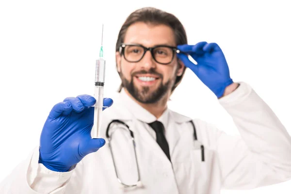 Крупним планом вид усміхненого лікаря в медичних рукавичках тримає шприц ізольовано на білому — стокове фото
