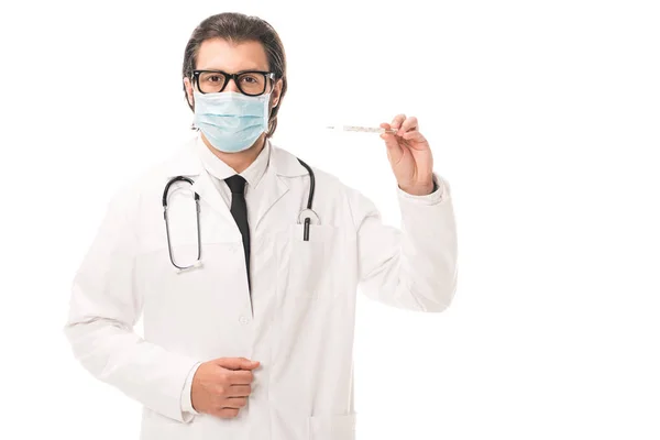 Doctor in medical mask holding thermometer and looking at camera isolated on white — Stock Photo