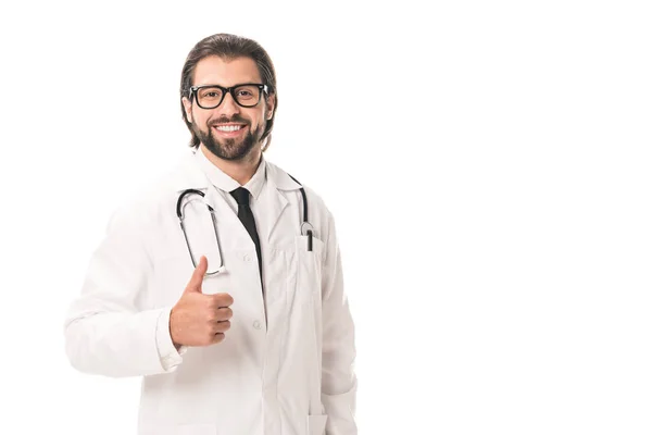 Guapo doctor en anteojos y bata blanca mostrando el pulgar hacia arriba y sonriendo a la cámara aislada en blanco - foto de stock