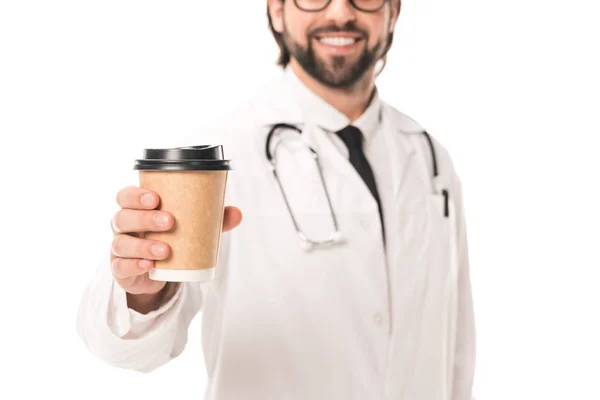 Abgeschnittene Aufnahme eines lächelnden Arztes in weißem Mantel, der eine Papptasse mit Kaffee to go auf weiß hält — Stockfoto