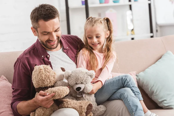 Father and daughter playing with teddy bears on father knees — Stock Photo