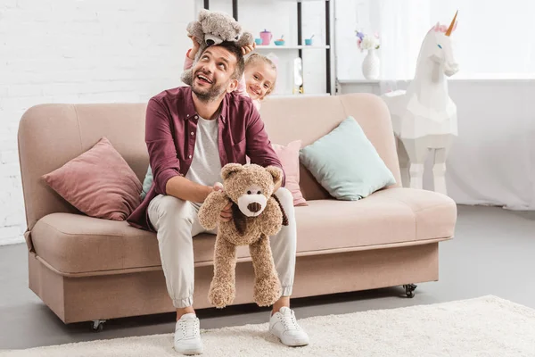 Pai e filha brincando com ursinhos de pelúcia no sofá — Fotografia de Stock