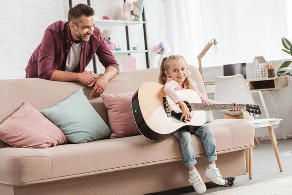 Father and daughter having fun and playing on guitar — Stock Photo