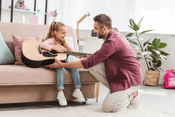 Cheerful dad and daughter having fun and playing on guitar — Stock Photo