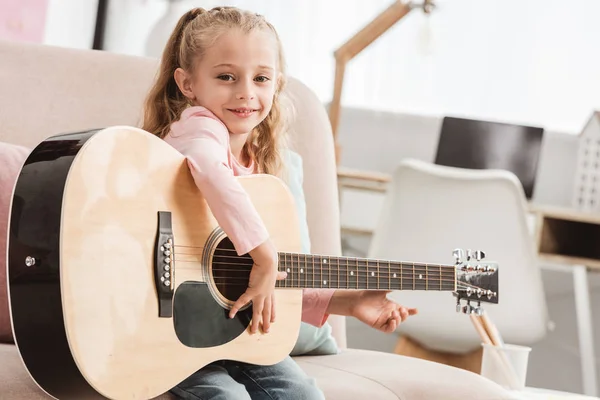 Bambino sorridente che suona la chitarra a casa — Foto stock