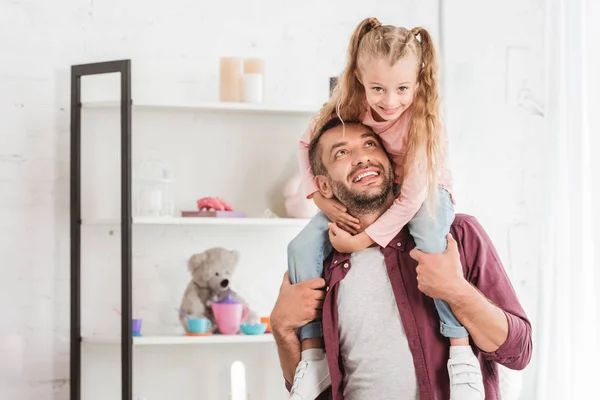 Tochter sitzt auf den Schultern des Vaters und umarmt sich zu Hause — Stockfoto