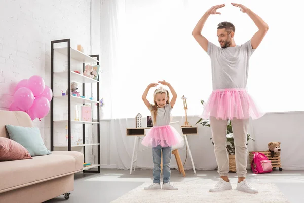 Father and daughter in pink tutu skirts dancing like ballerinas — Stock Photo