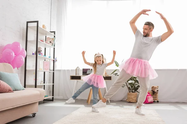 Funny father and daughter in pink tutu skirts dancing like ballerinas — Stock Photo