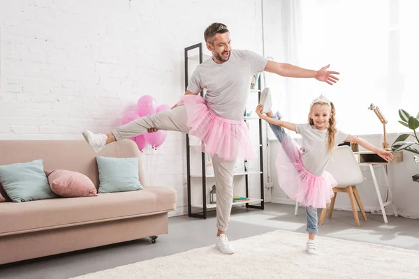 Front view of father and daughter in tutu skirts standing on one leg — Stock Photo