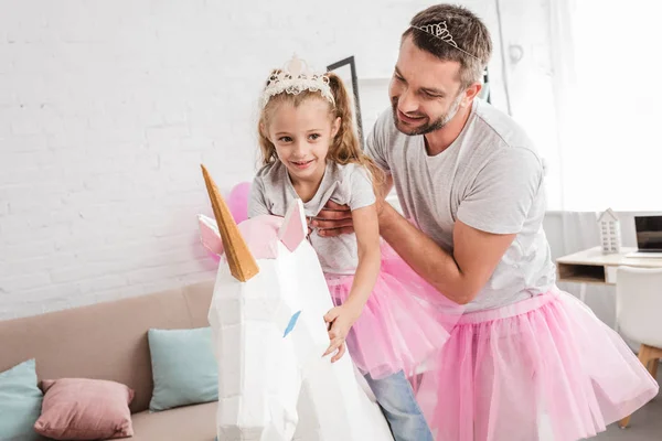 Padre sosteniendo hija cabalgando en unicornio - foto de stock