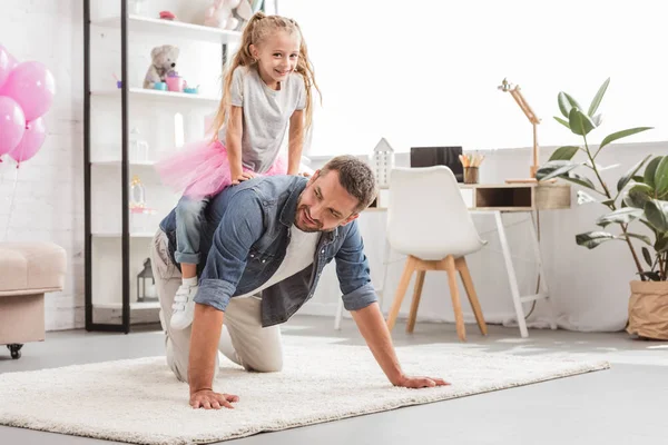 Daughter sitting on on father back and smiling at home — Stock Photo