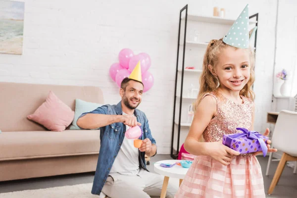 Padre e hija en sombreros de cono jugando fiesta de té en casa - foto de stock