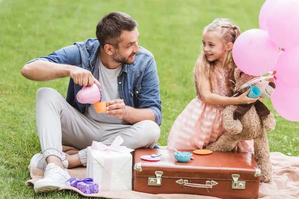 Padre e hija jugando al té en el césped - foto de stock