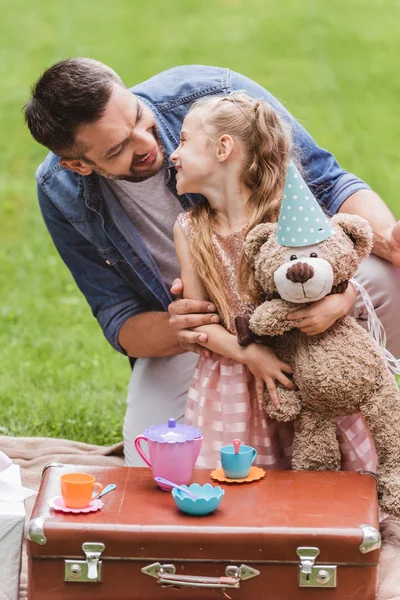 Батько і дочка з плюшевим ведмедем грають на чайній вечірці на газоні — стокове фото
